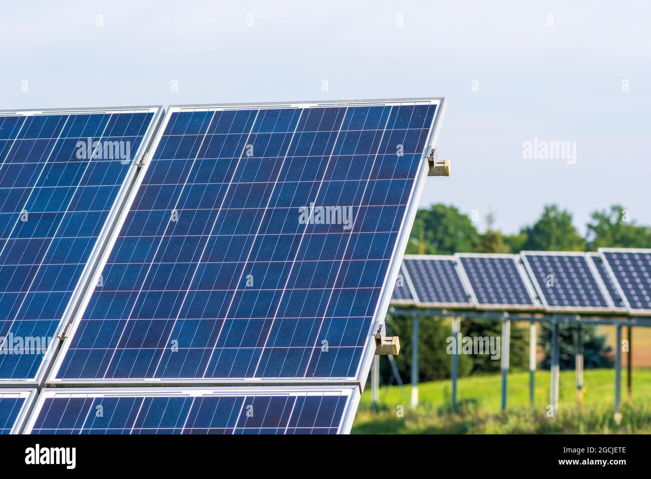 Pannelli solari in un campo agricolo verde in campagna. Impianto solare. Pannelli solari blu. Fonte alternativa di elettricità. Fattoria solare Foto Stock
