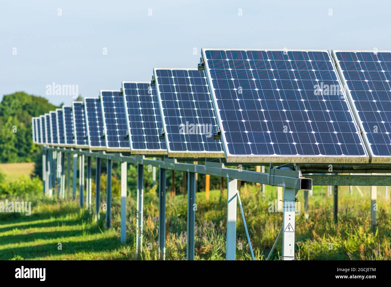 Pannelli solari in un campo agricolo verde in campagna. Impianto solare. Pannelli solari blu. Fonte alternativa di elettricità. Fattoria solare Foto Stock