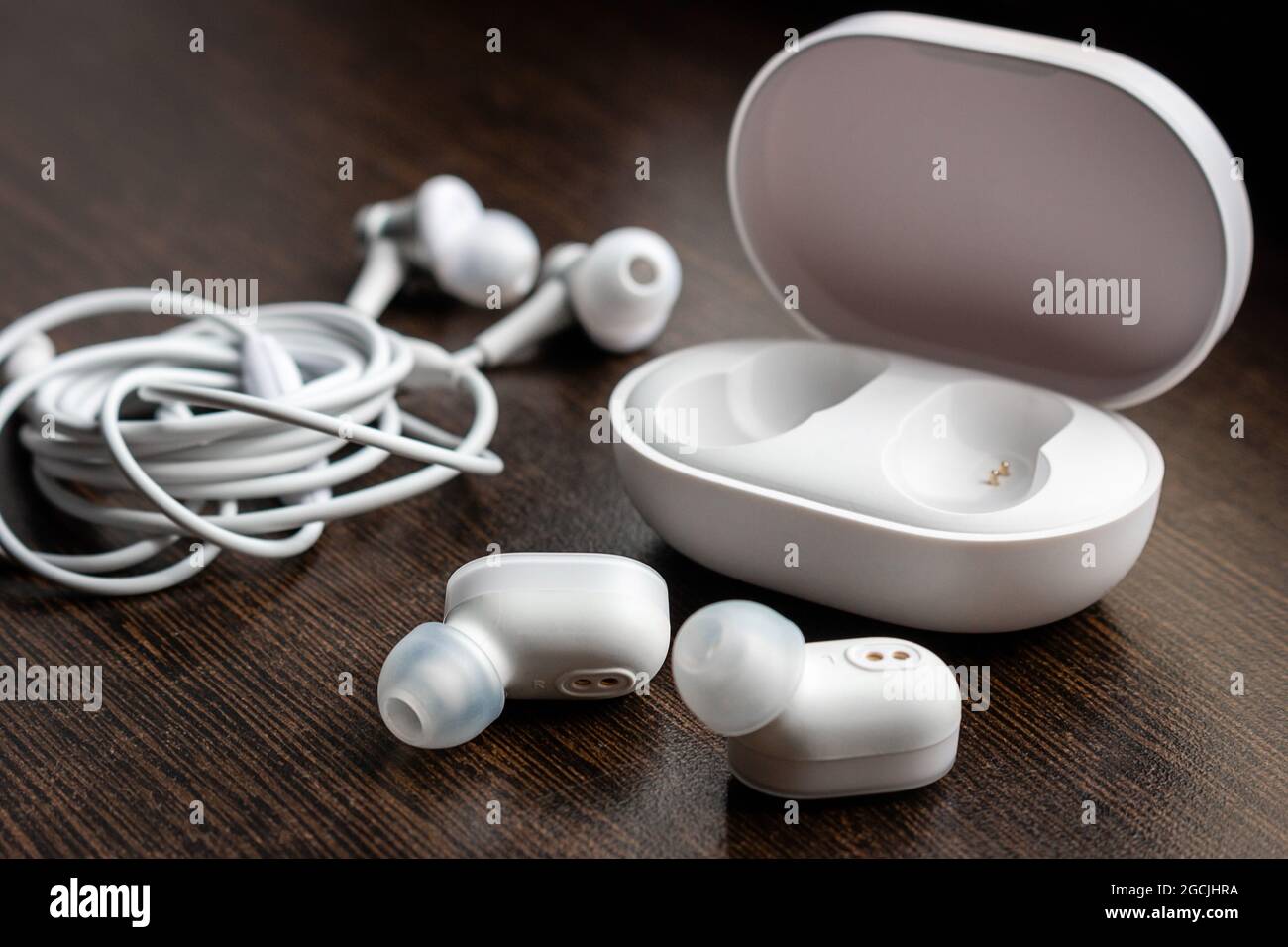 cuffie wireless bluetooth, caricabatterie e cuffie aggrovigliate su sfondo  in legno Foto stock - Alamy