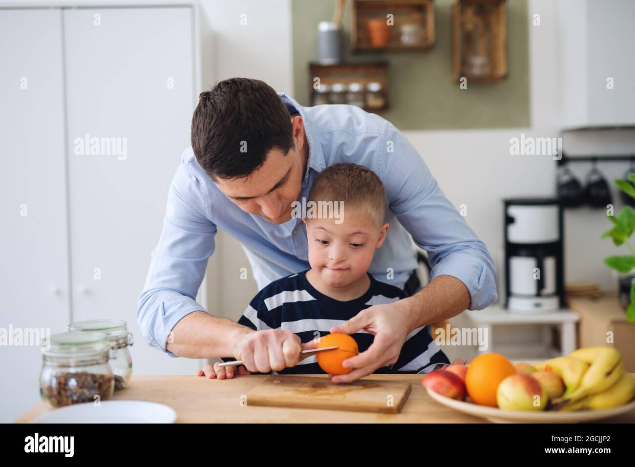 Padre con il figlio della sindrome di Happy Down all'interno della cucina, preparando il cibo. Foto Stock