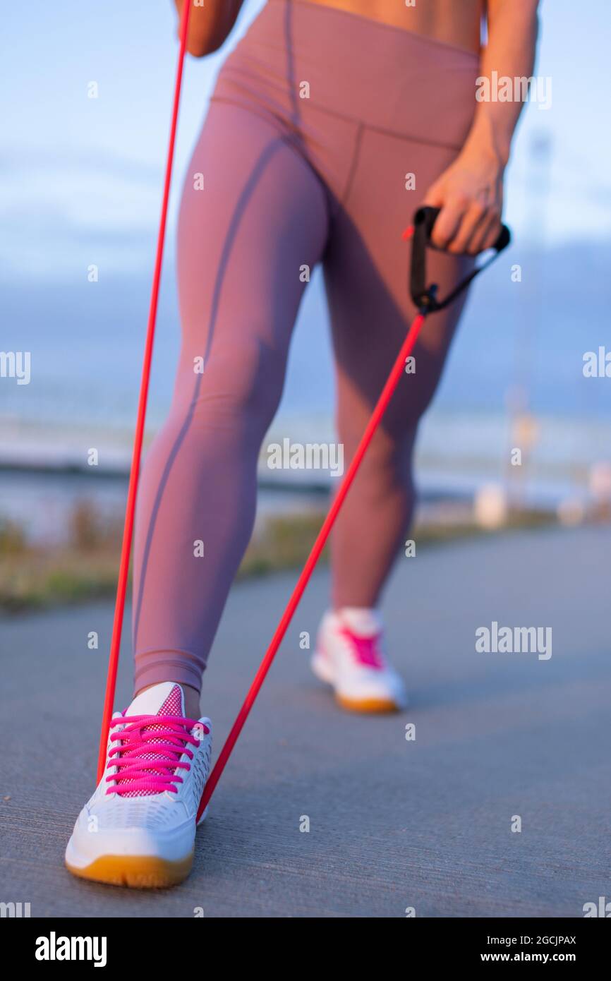 Gambe donna in abbigliamento sportivo facendo esercizio stretching da espansore all'aperto Foto Stock