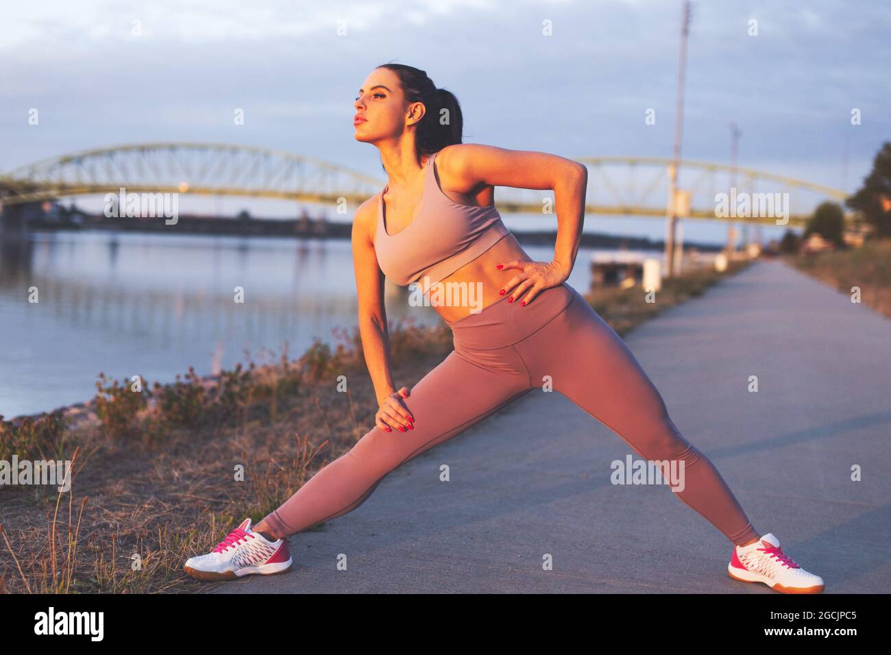 Giovane donna jogger caucasica che allunga le gambe prima di correre a riva Foto Stock