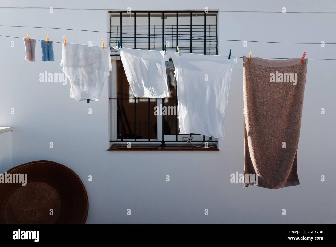 Lavanderia lavata appesa alla stendibiancheria nel cortile della casa di campagna con pareti bianche e finestra grata Foto Stock