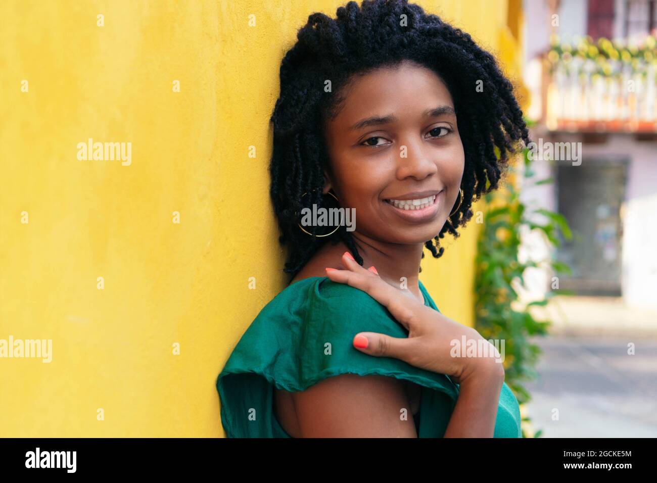 Chiudi ritratto a testa in alto di una bella giovane donna nera sorridente appoggiata al muro esterno Foto Stock