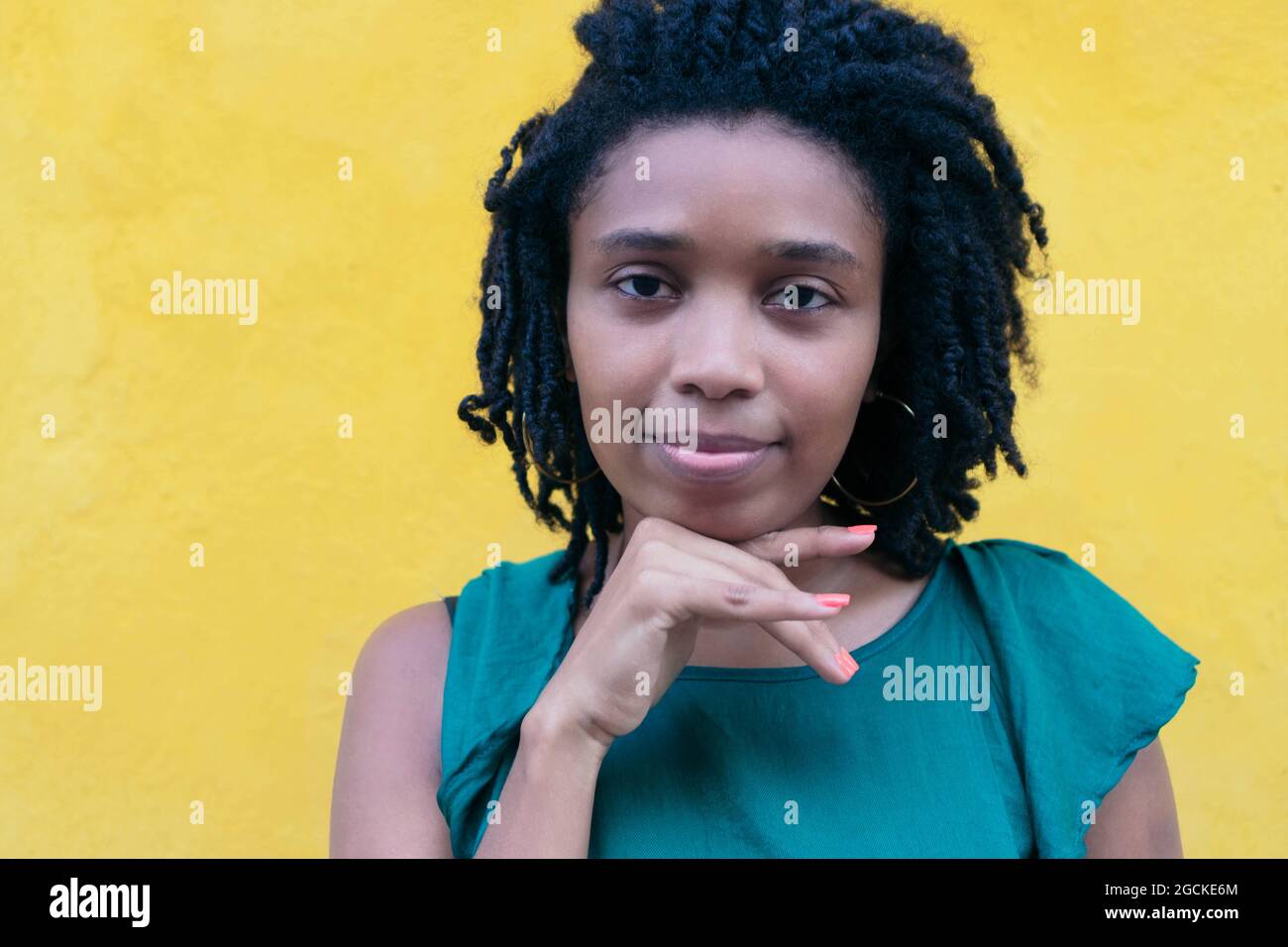 Ritratto di giovane donna africana con acconciatura afro appoggiata su un muro Foto Stock