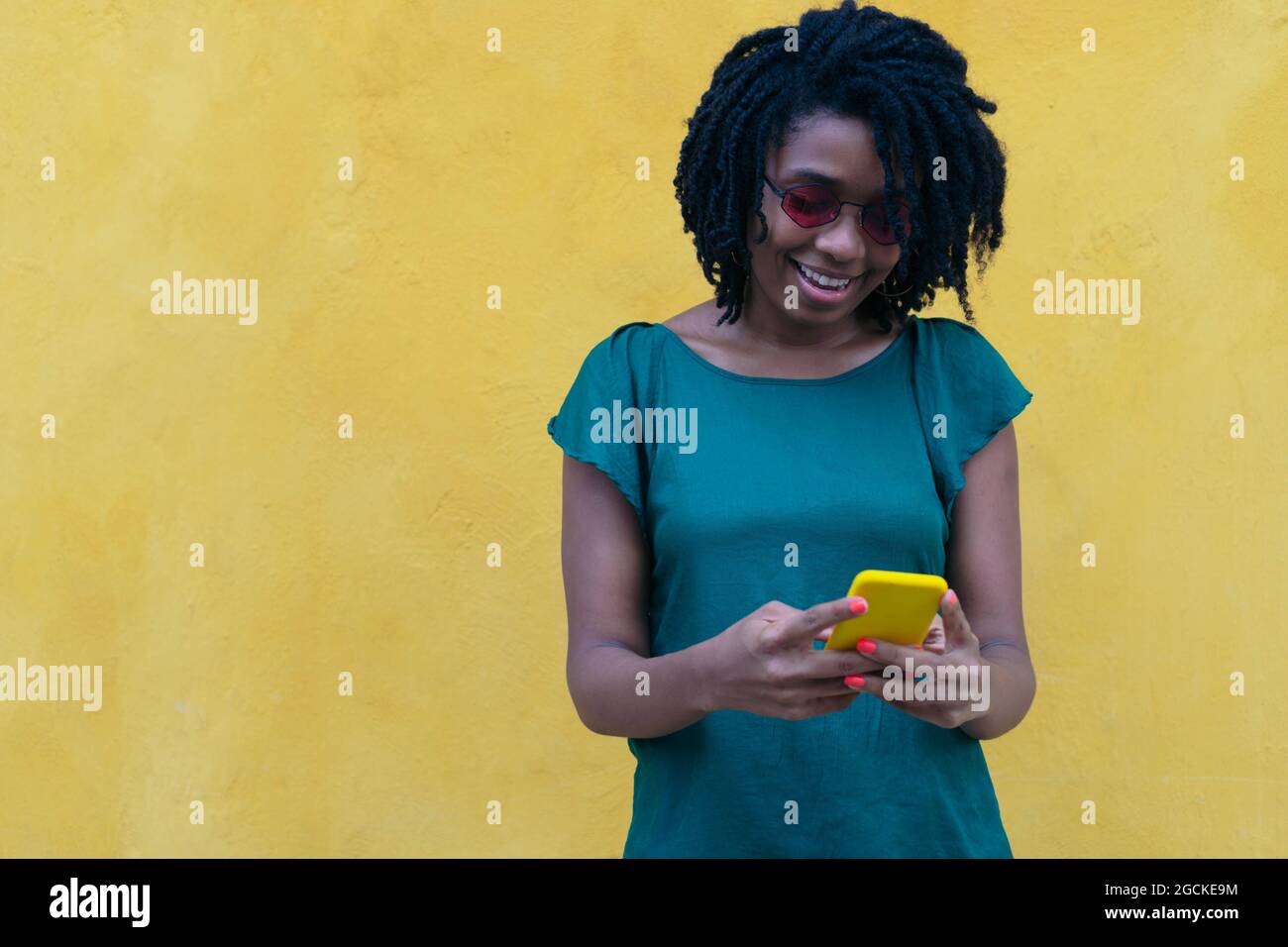 Felice giovane donna che controlla il suo cellulare per strada Foto Stock