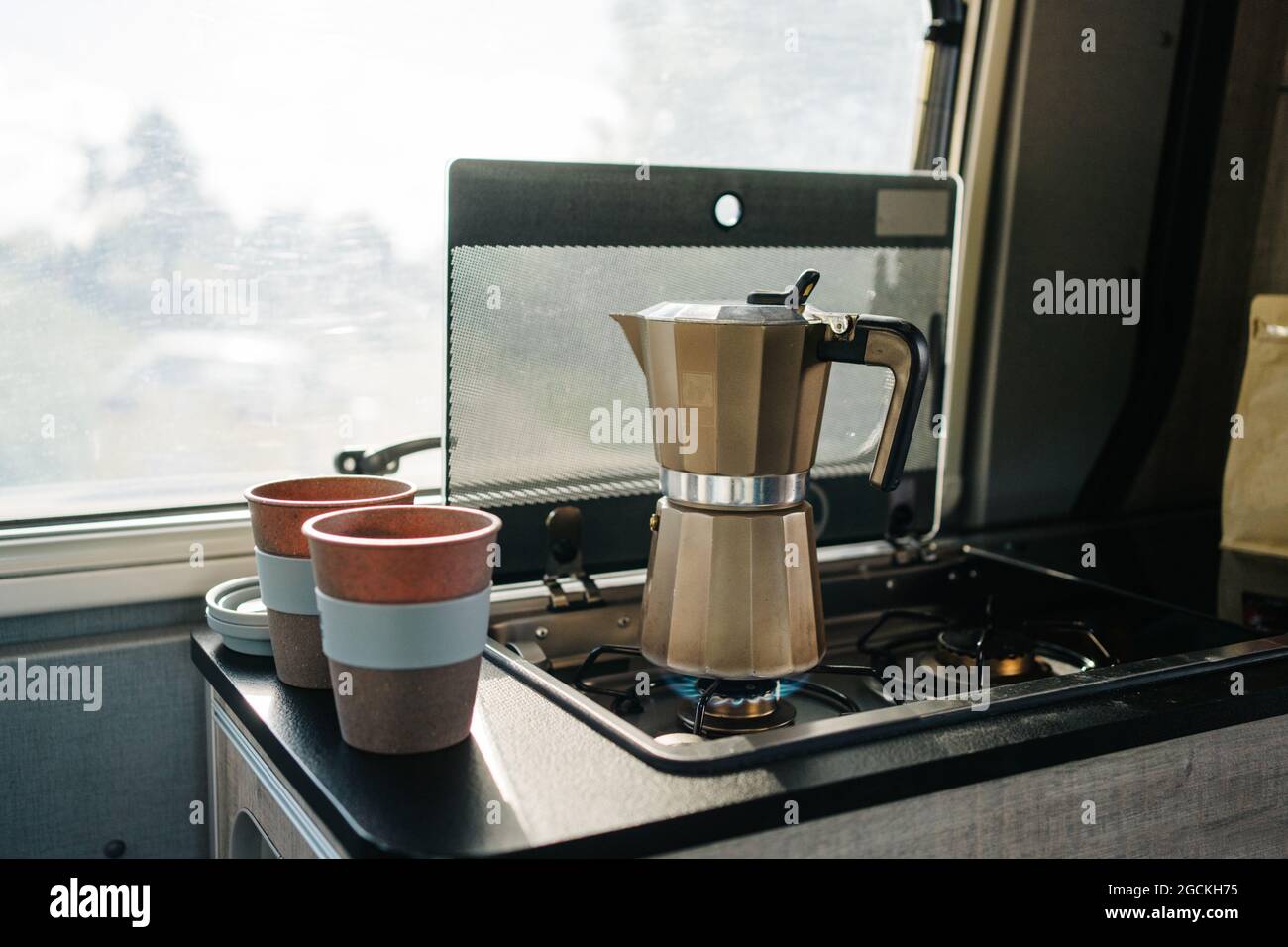 Il caffè si riscalda nella cucina di una motocicletta accanto a due tazze Foto Stock