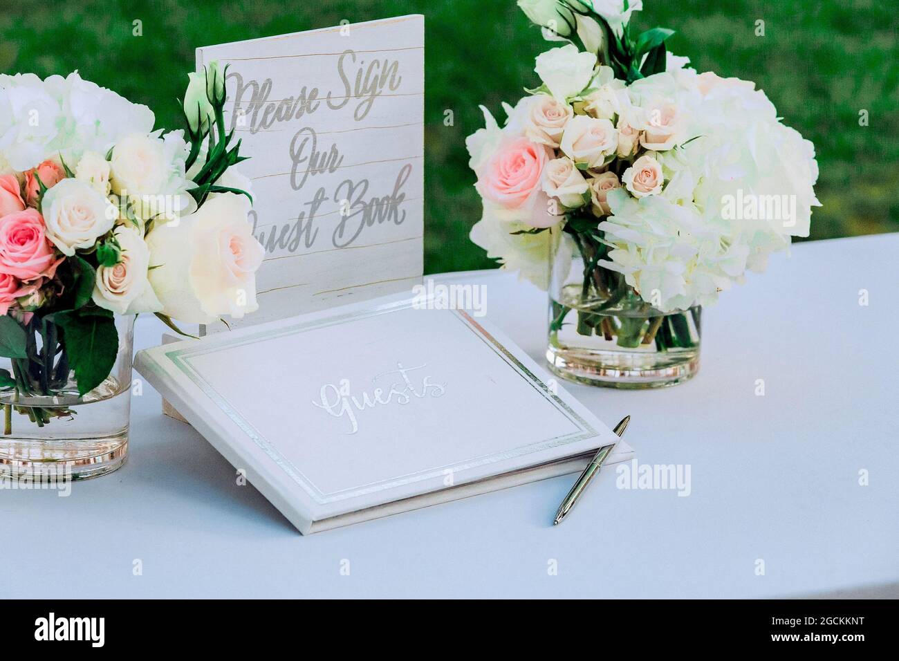 Un mazzo di fiori in vasi su un tavolo e un Libro degli ospiti Foto Stock