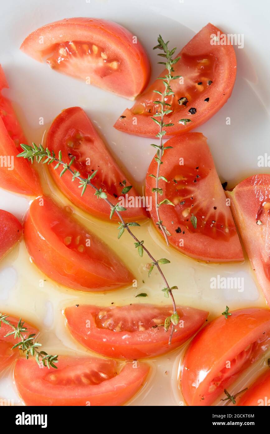 Vista dall'alto di appetitosi pezzi di pomodoro con erbe verdi servite sul piatto sul tavolo Foto Stock