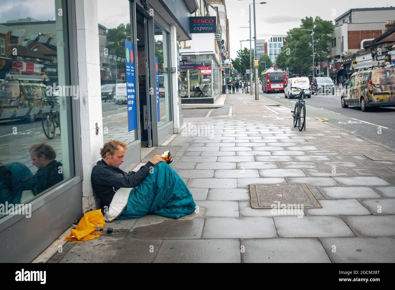 Londra- Agosto 2021: Un uomo senza tetto siede sul marciapiede nella West Ealing High Street Foto Stock