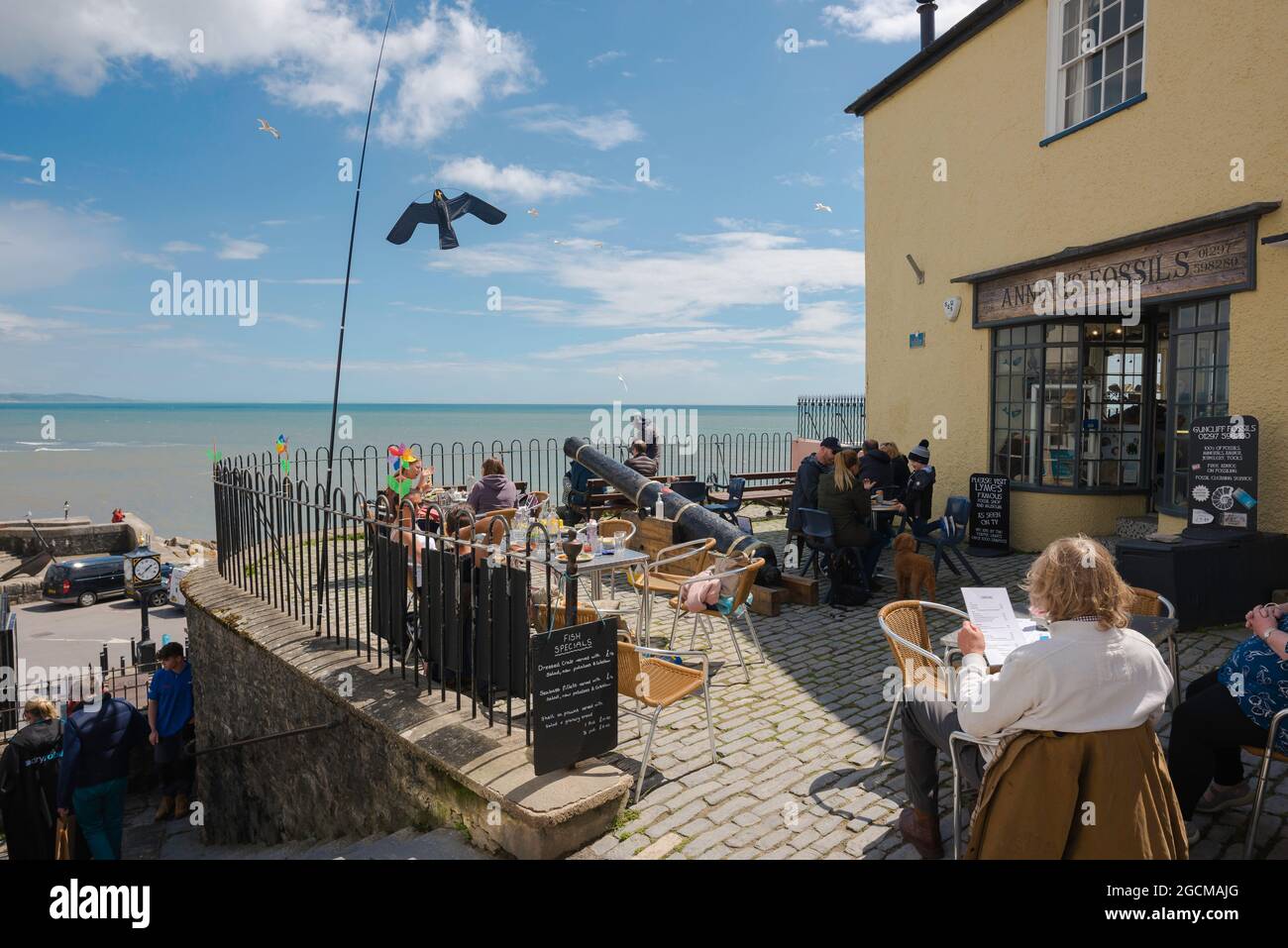 Dorset costa, vista di persone che si rilassano su una terrazza caffè che si affaccia sul lungomare di Lyme Regis, Dorset, Inghilterra, Regno Unito Foto Stock