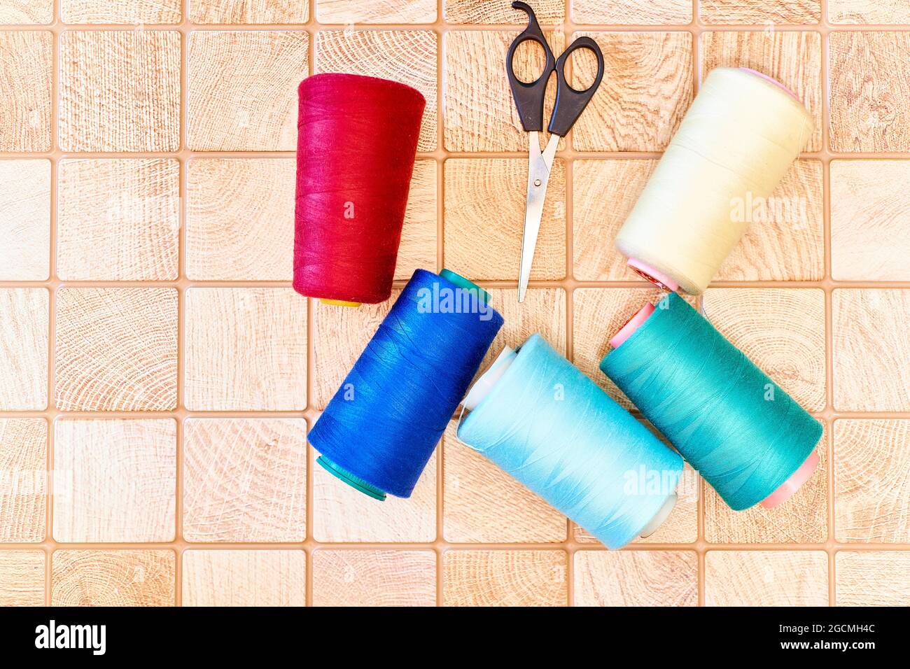 Fili colorati e forbici, attrezzature per la sartoria sul piano di lavoro Foto Stock