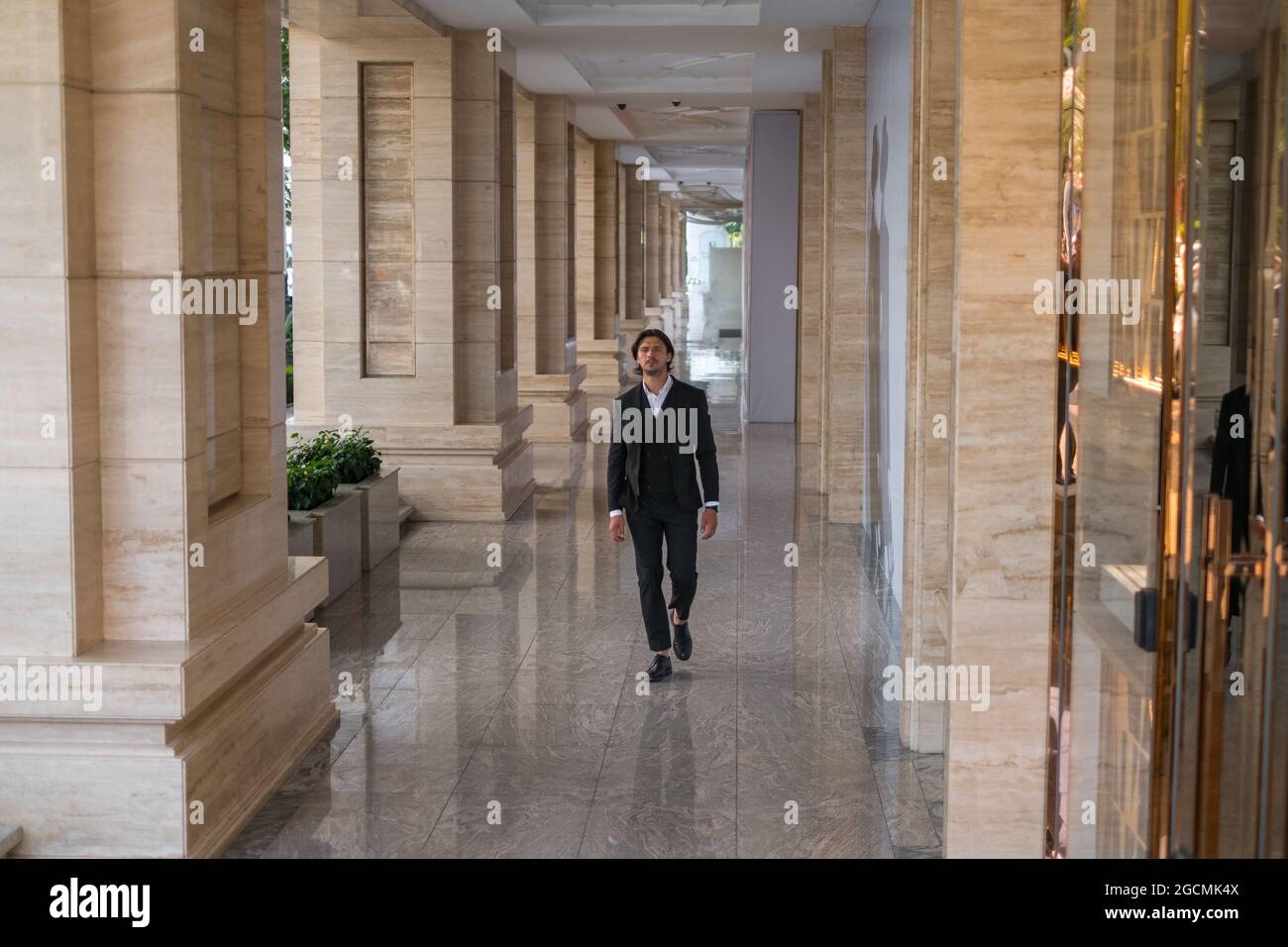 Lavoratore in tuta nera che cammina sulla strada vicino a un moderno edificio di uffici. . Foto di alta qualità Foto Stock