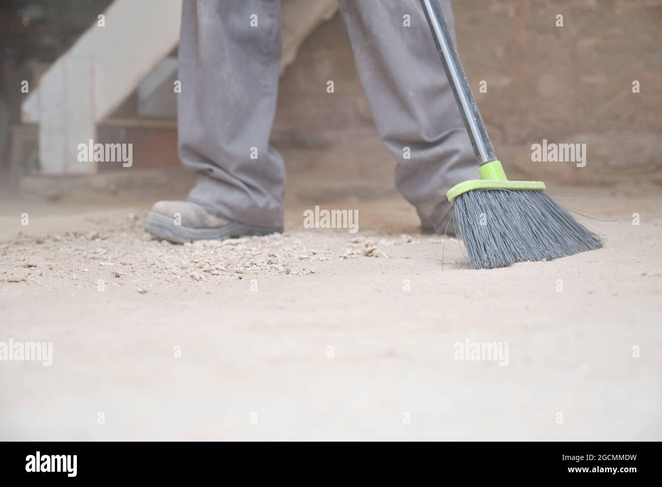 Irriconoscibile giovane costruttore che spazzano il pavimento in un cantiere. Foto Stock
