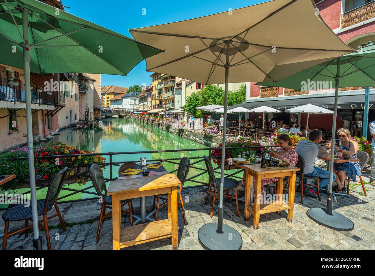 I turisti si siedono ai tavoli in un caffè su uno dei ponti che attraversano il fiume Thiou nella città vecchia di Annecy. Annecy, dipartimento della Savoia, Francia Foto Stock