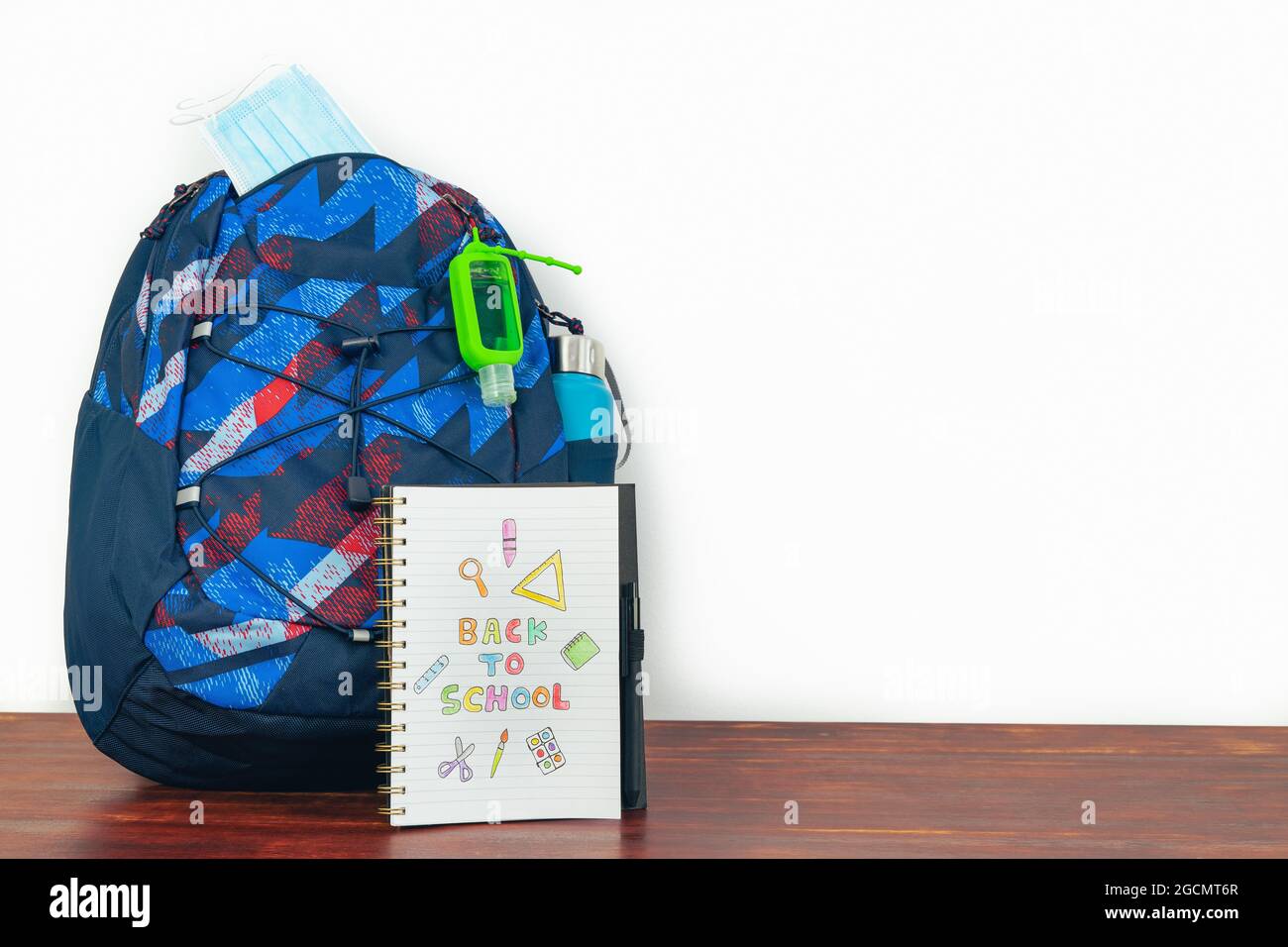 Notebook con testo DI RITORNO A SCUOLA con zaino e sfondo bianco. Spazio di copia. Foto Stock