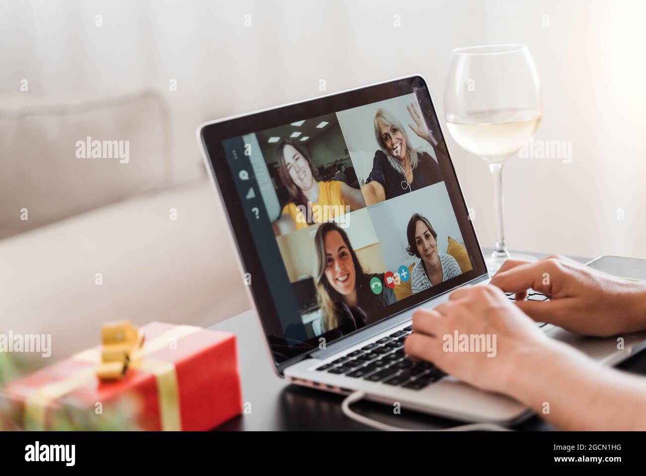 Multi generazionale famiglia in videochiamata per celebrare natale online in conferenza di gruppo meeting con vino utilizzando computer portatile - Focus su schermo Foto Stock