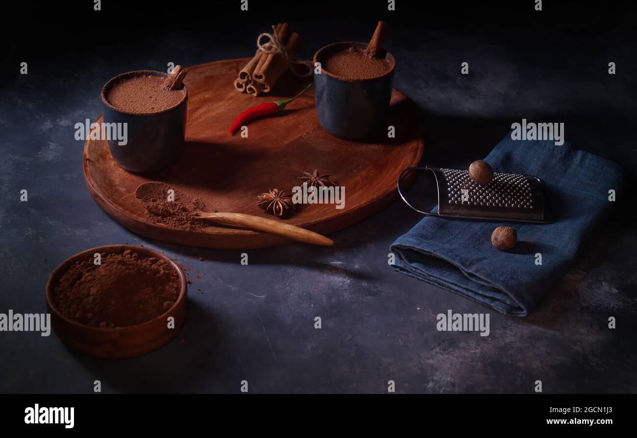 Preparazione di una bevanda piccante di cacao da vera polvere di coca. Gustosa bevanda sana per colazione, brunch o cena. Tabella sfondo scuro. Foto Stock