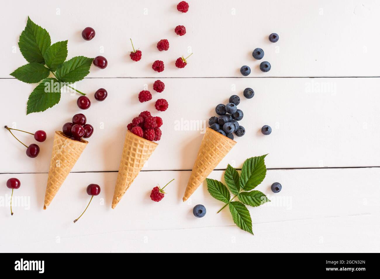 Frutta di fondo. Frutta fresca e bacche in coni di waffle. Concetto estivo. Disposizione piatta, vista dall'alto Foto Stock