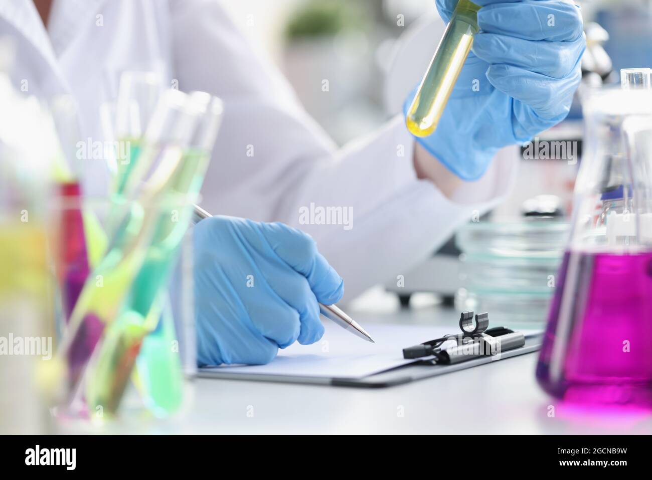 Il ricercatore registra i dati ottenuti da esperimenti chimici in laboratorio. Tipi di concetto di reazioni chimiche Foto Stock