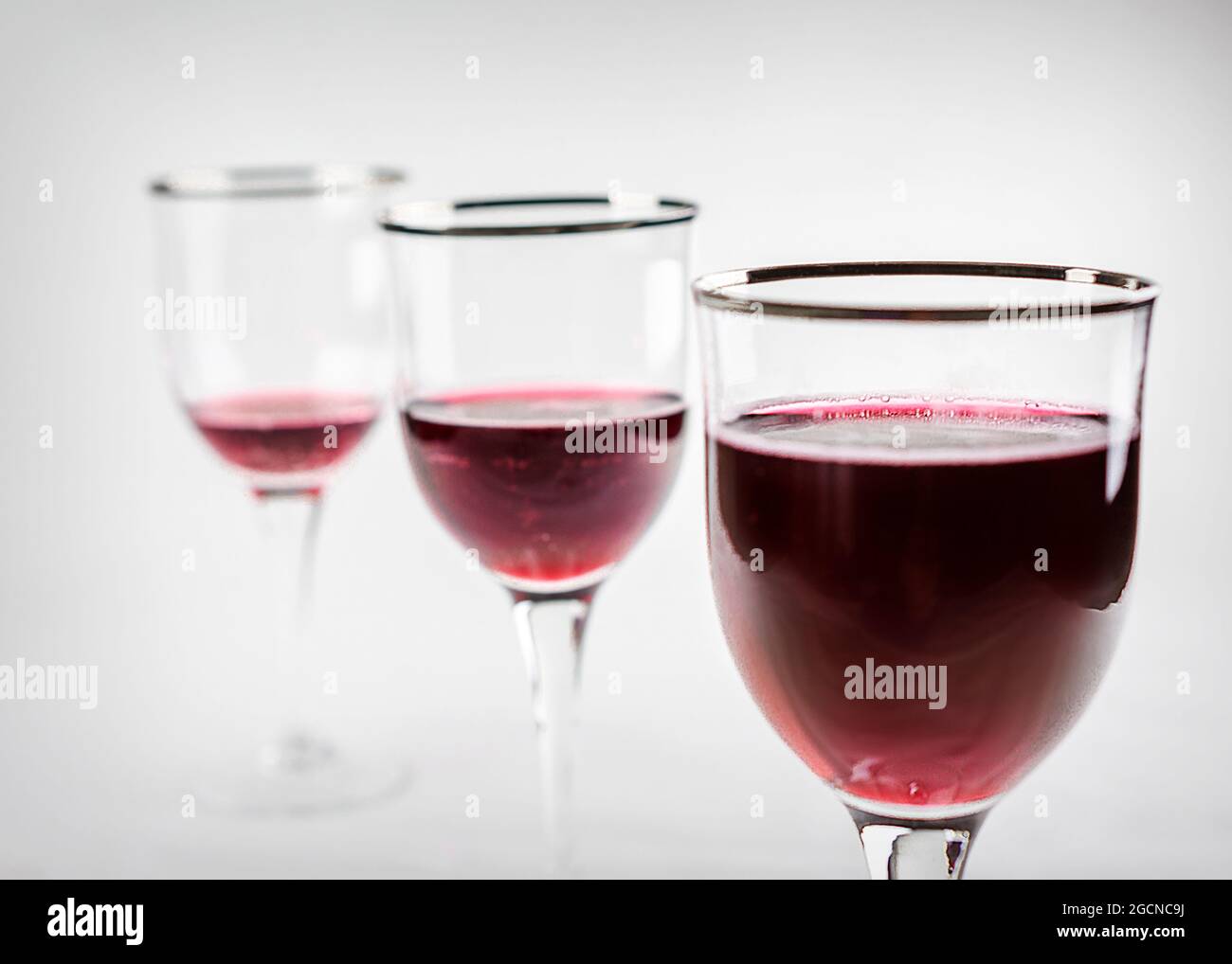 Tre bicchieri di vino in fila in cui i loro livelli di vino sono livellato. Mettere a fuoco il vetro anteriore mentre gli altri occhiali sfocano sullo sfondo. Foto Stock
