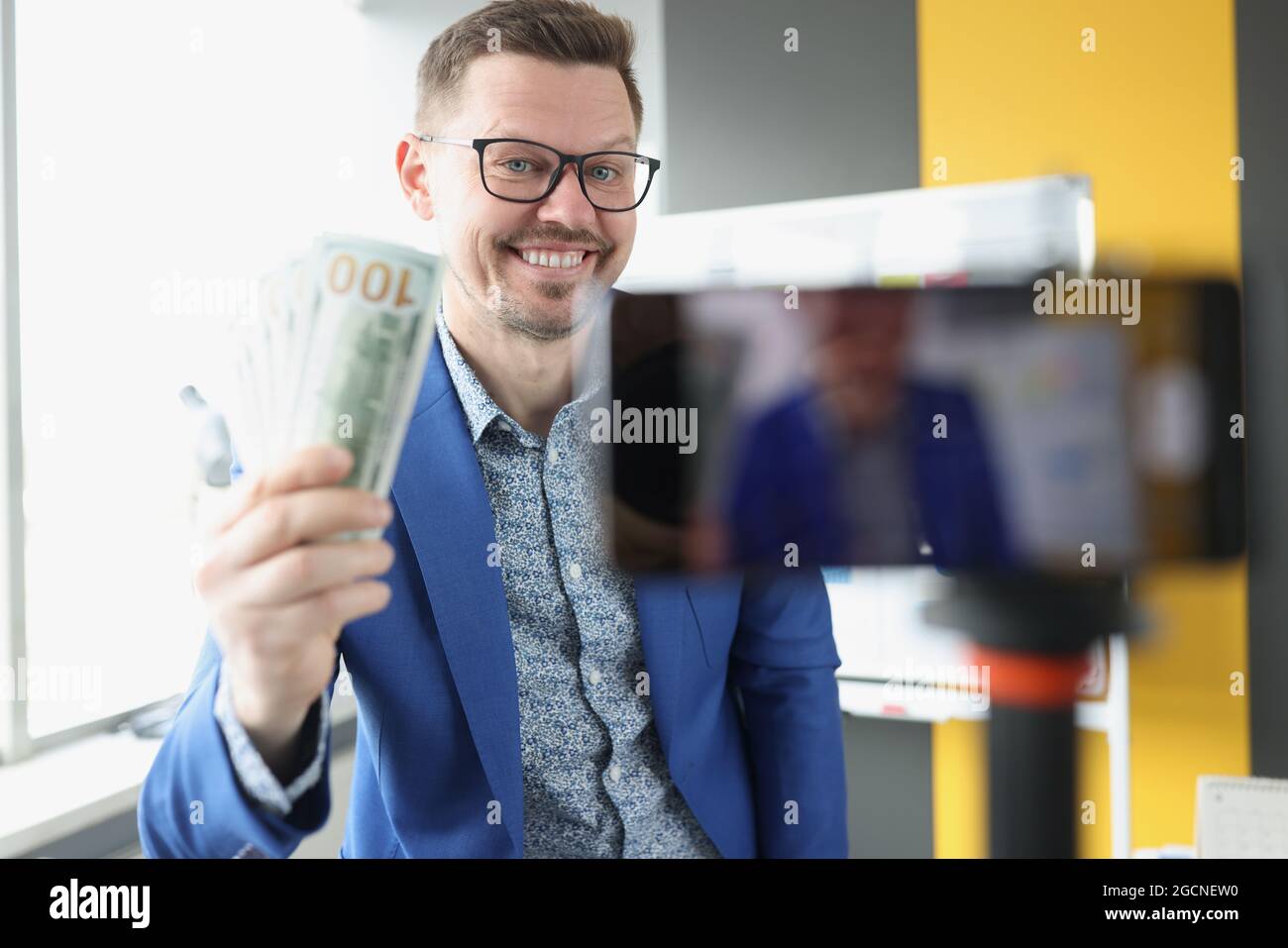 Blogger sorridente dimostra denaro un centinaio di dollari bollette a macchina fotografica Foto Stock