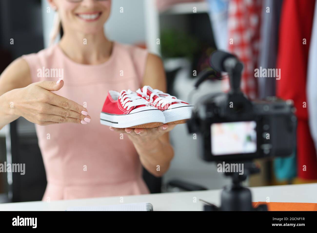 Donna venditore consulente mostra a macchina fotografica scarpe sportive rosse Foto Stock