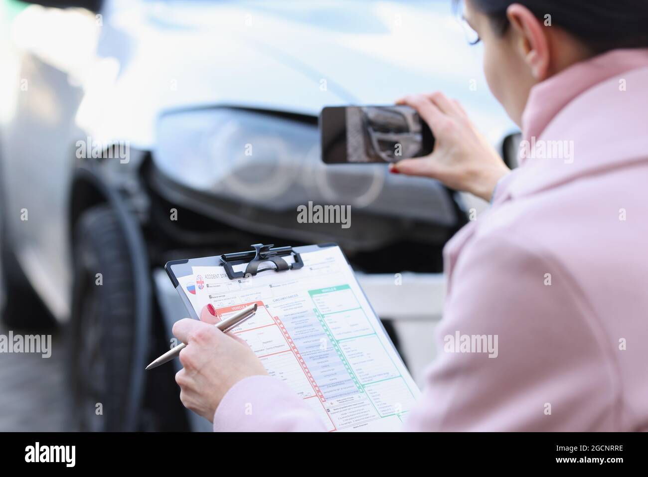 L'agente assicurativo sta filmando i danni all'auto dopo l'incidente Foto Stock