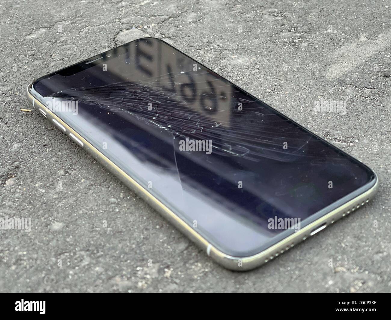 MOSCA, RUSSIA - 29 luglio 2021: Incrinature sul vetro di un telefono cellulare. Si trova sull'asfalto grigio Foto Stock