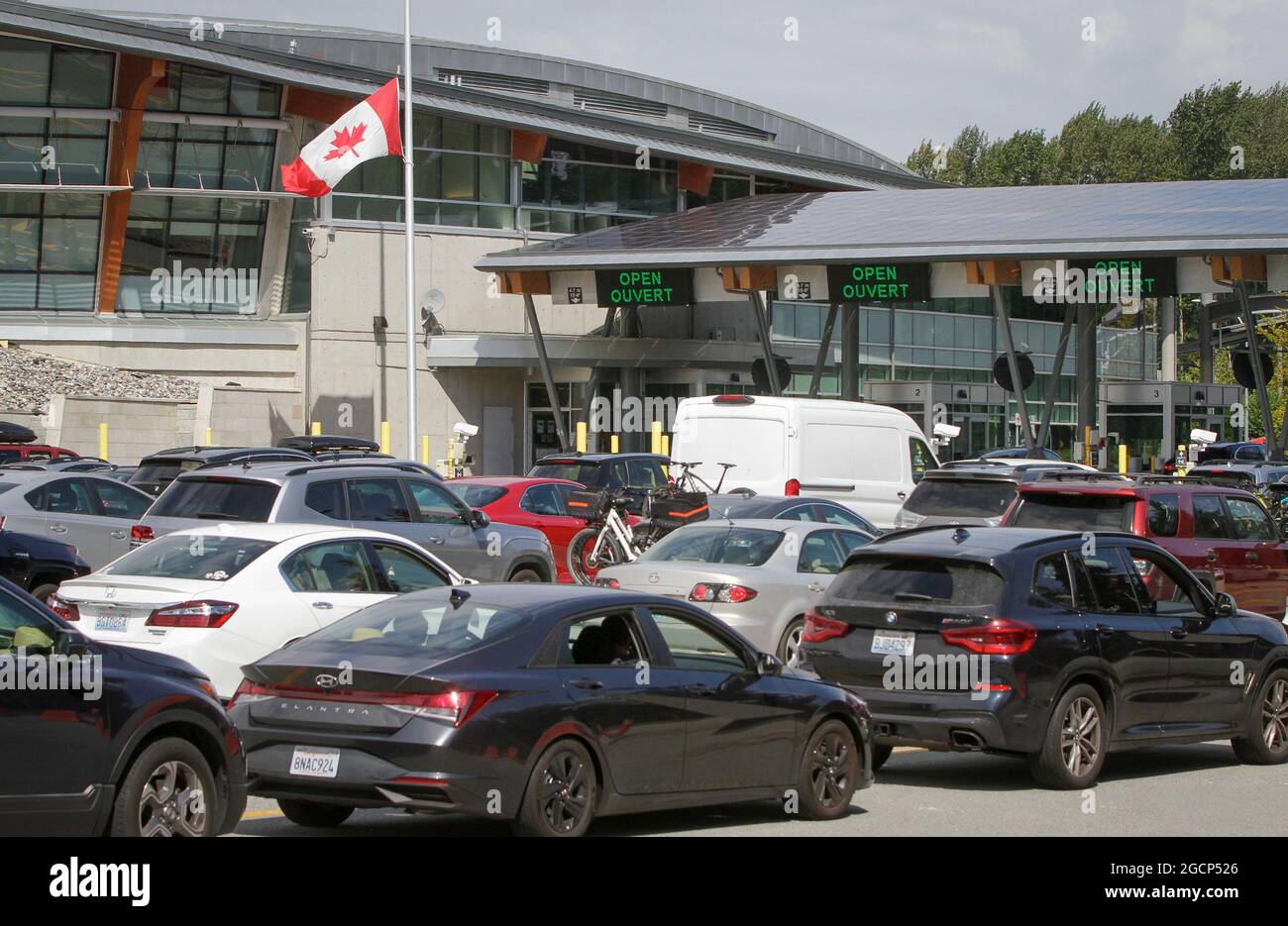 Surrey, Canada. 9 agosto 2021. I veicoli si allineano per entrare in Canada all'attraversamento del confine dell'arco della Pace a Surrey, British Columbia, Canada, il 9 agosto 2021. Il Canada ha iniziato unilateralmente a consentire l'ingresso da parte di cittadini statunitensi e residenti permanenti completamente vaccinati lunedì dopo che i due paesi hanno accettato di chiudere il confine a viaggi non essenziali a causa della pandemia COVID-19 17 mesi fa. Credit: Liang Sen/Xinhua/Alamy Live News Foto Stock