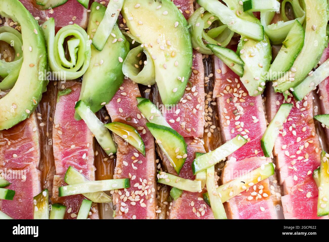Foto ravvicinata del tonno scottato con semi di sesamo, cetriolo e avocadi Foto Stock