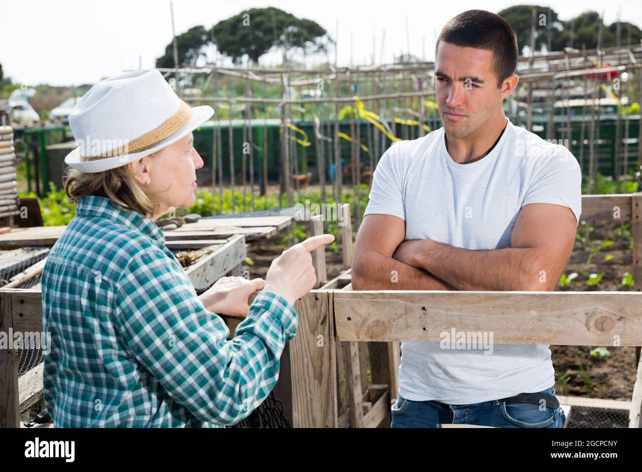 Orticoltore maschile che parla con nonna vicino a travi di legno Foto Stock