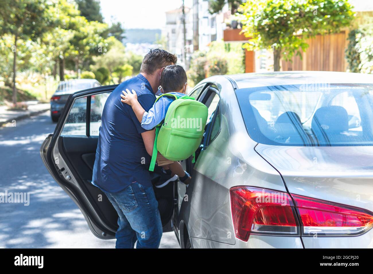 Padre che porta suo figlio con lo zaino in macchina per andare a scuola Foto Stock