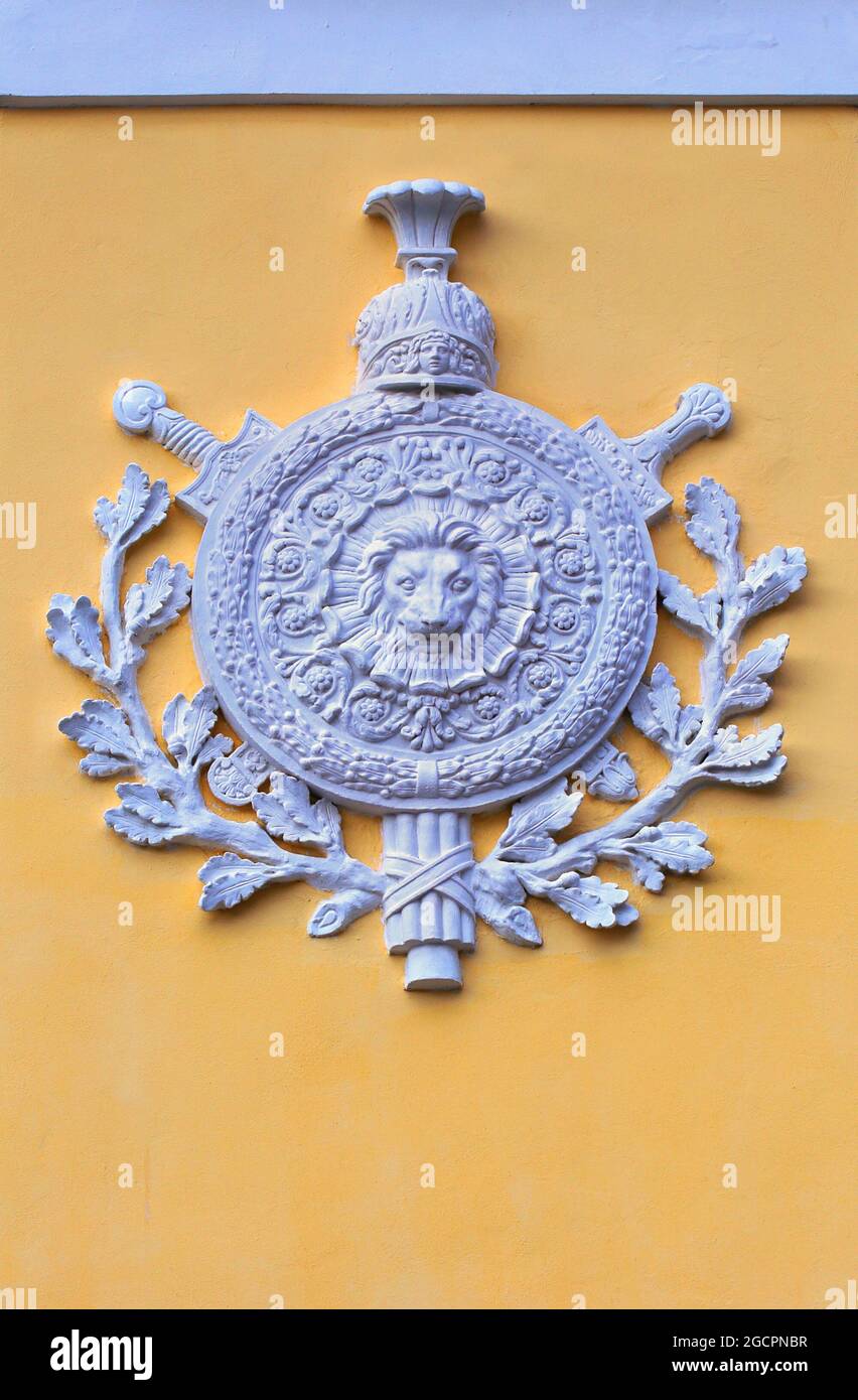 Antico stemma dell'intonaco bianco su una parete gialla a forma di scudo rotondo coronato da allori Foto Stock