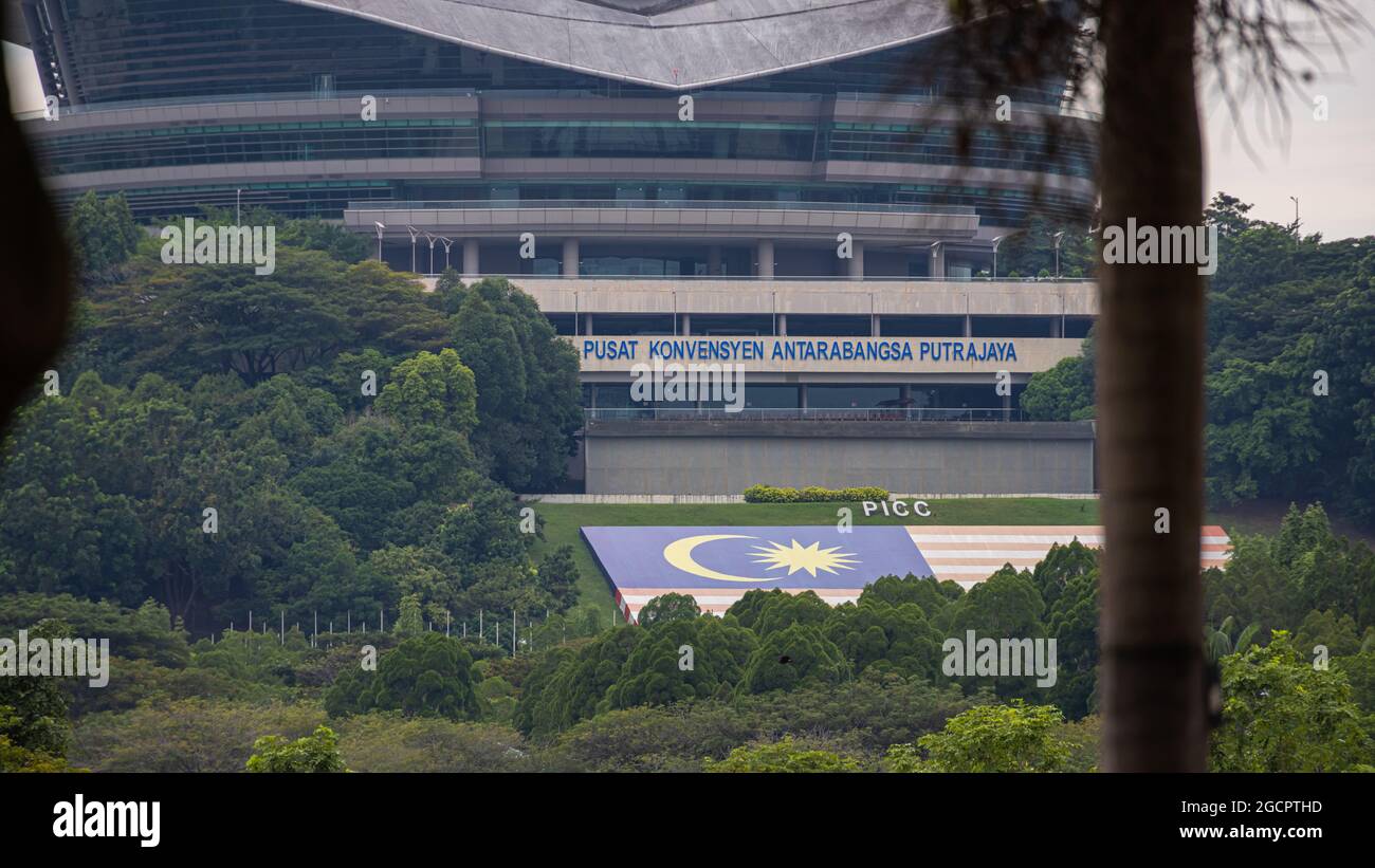 Putrajaya, Malesia - 11 ottobre 2020: Il centro congressi internazionale di Putrajaya. In primo piano la grande bandiera malese di fronte alla costruzione Foto Stock