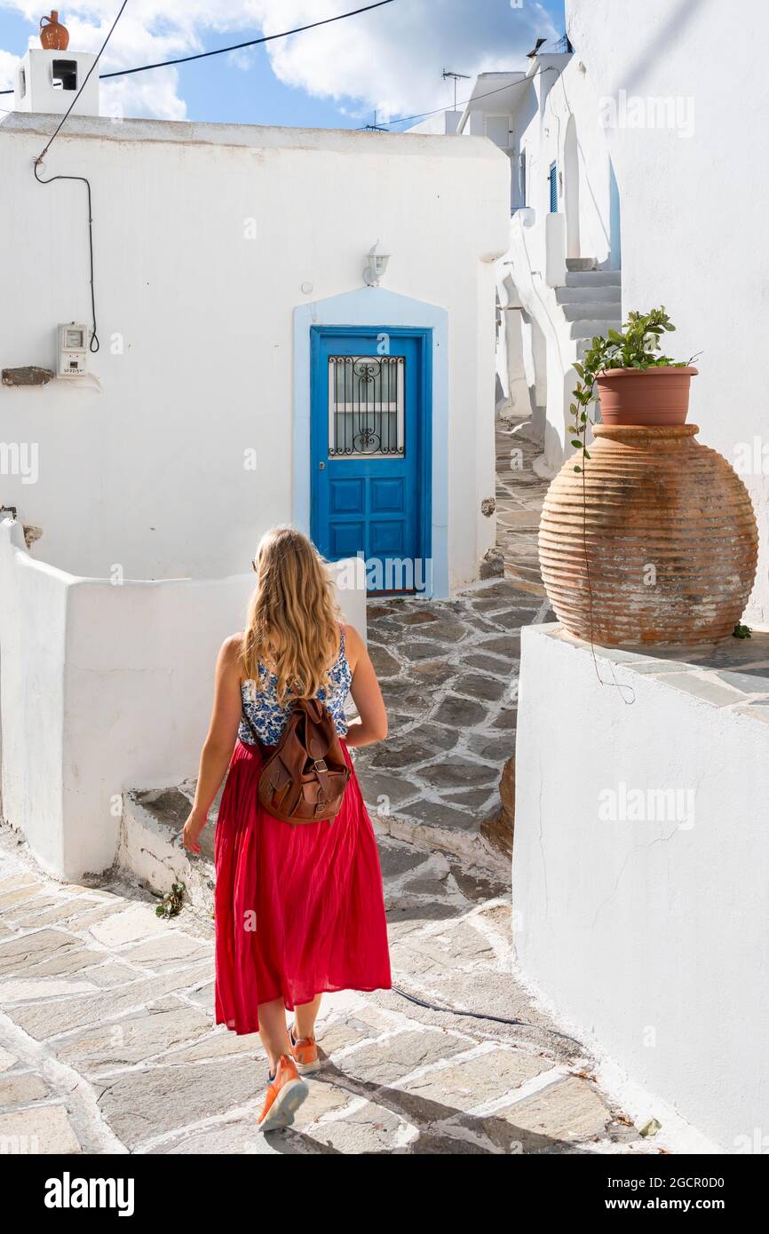 Case bianche e blu delle Cicladi, giovane donna con abito rosso nel centro storico di Lefkes, Paros, Cicladi, Grecia Foto Stock