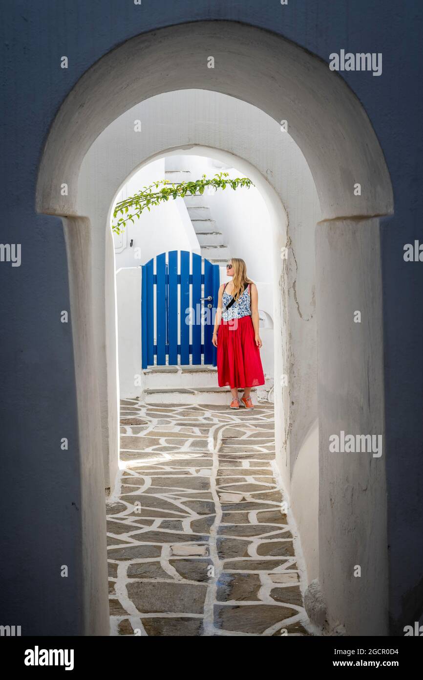 Archi bianchi tra case, giovane donna con abito rosso nel centro storico di Lefkes, Paros, Cicladi, Grecia Foto Stock