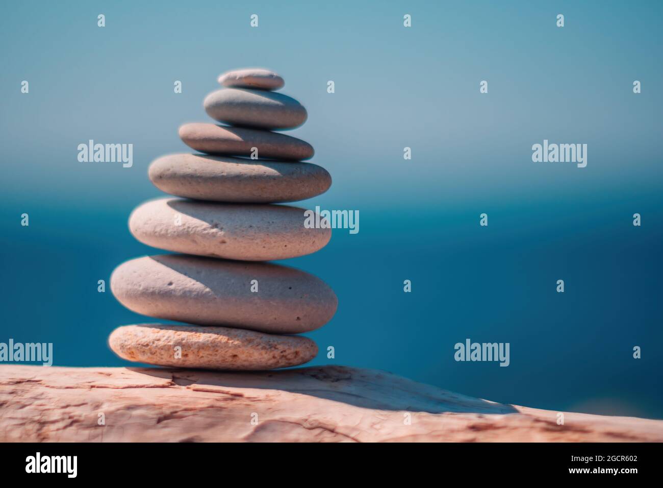 Equilibrata piramide di ciottoli sulla spiaggia in una giornata di sole. Abstract Sea bokeh sullo sfondo. Messa a fuoco selettiva. Pietre Zen sulla spiaggia di mare, meditazione Foto Stock