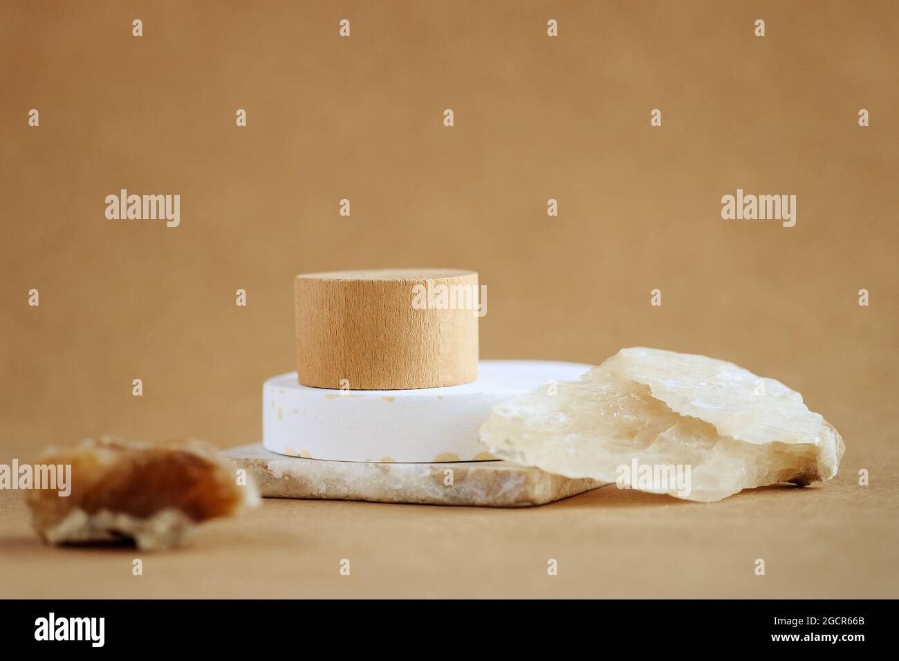 Scena minimalista astratta con pietre naturali. Podio in legno cilindrico su sfondo beige. Presentazione del prodotto, mock up, mostra prodotto cosmetico, Podium, piedistallo o piattaforma. Foto Stock