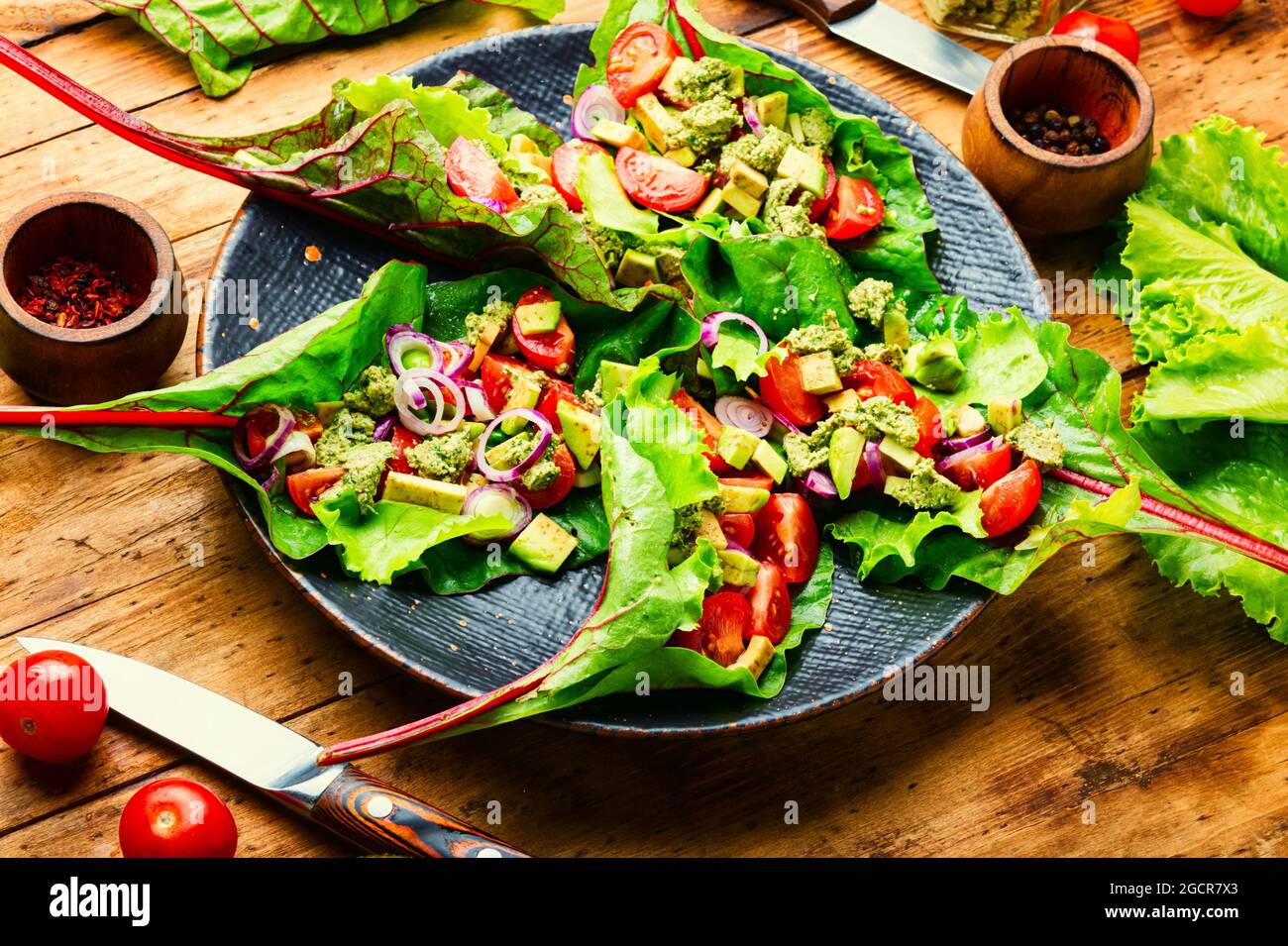 Insalata di avocado, pomodoro con salsa all'aglio in foglie di bietole. Insalata di vitamina estiva in piatto Foto Stock