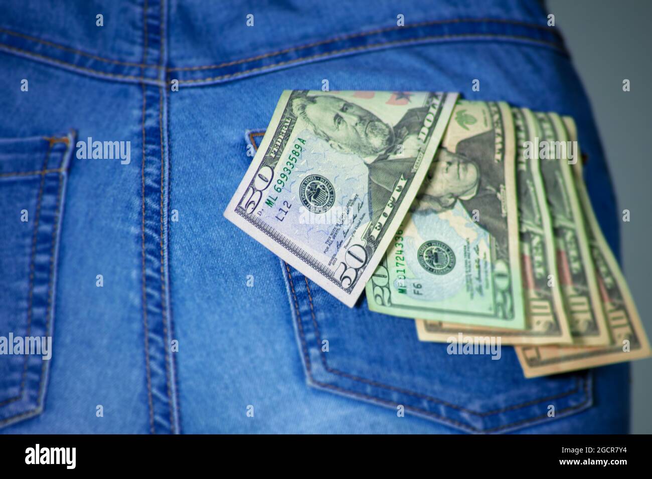 Una collezione di dollari USA in una tasca di jeans femmina, un po 'di soldi tascabili, vicino a 50 dollari. Dollari americani bloccati nella tasca della donna. Il dollaro t Foto Stock