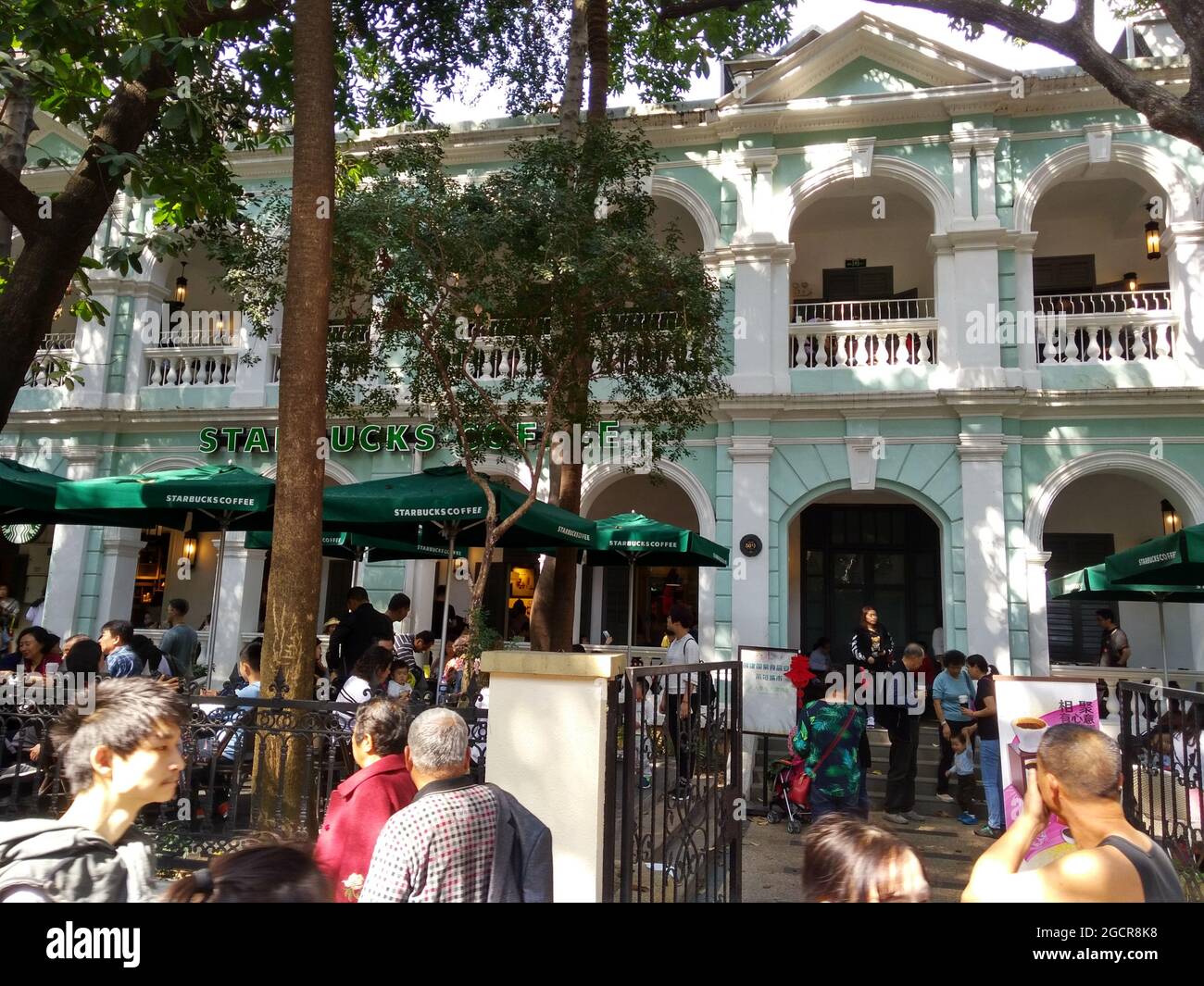 Il popolare Starbucks sull'Isola di Shamian in Guangzhou, pieno di gente del posto e turisti, ma nascosto dietro gli alberi. Foto Stock