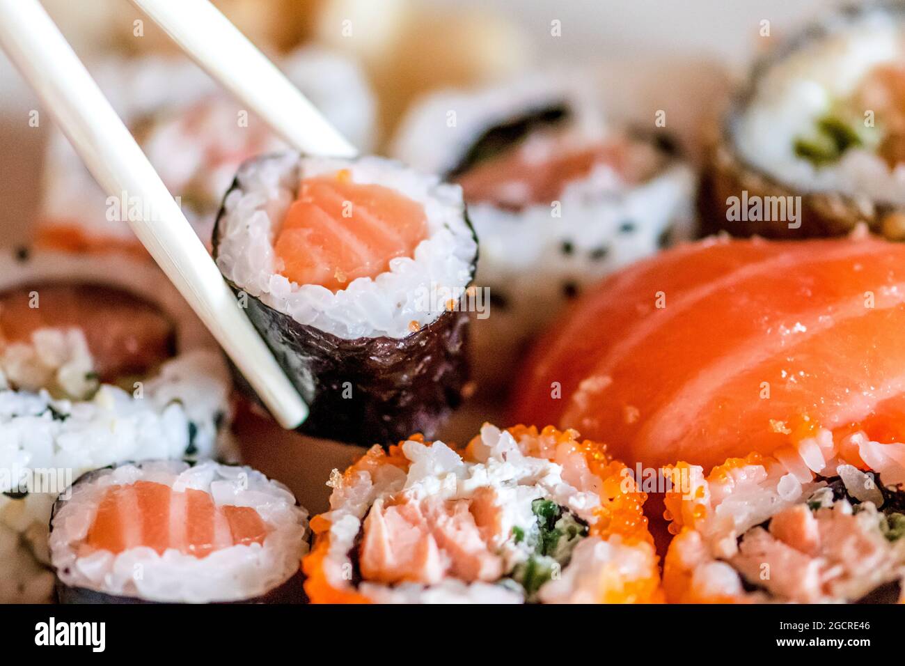 Mangiare vari sushi. Maki, uramaki, hosomaki, sahimi e nigiri in un piatto con bacchette di bambù, primo piano Foto Stock