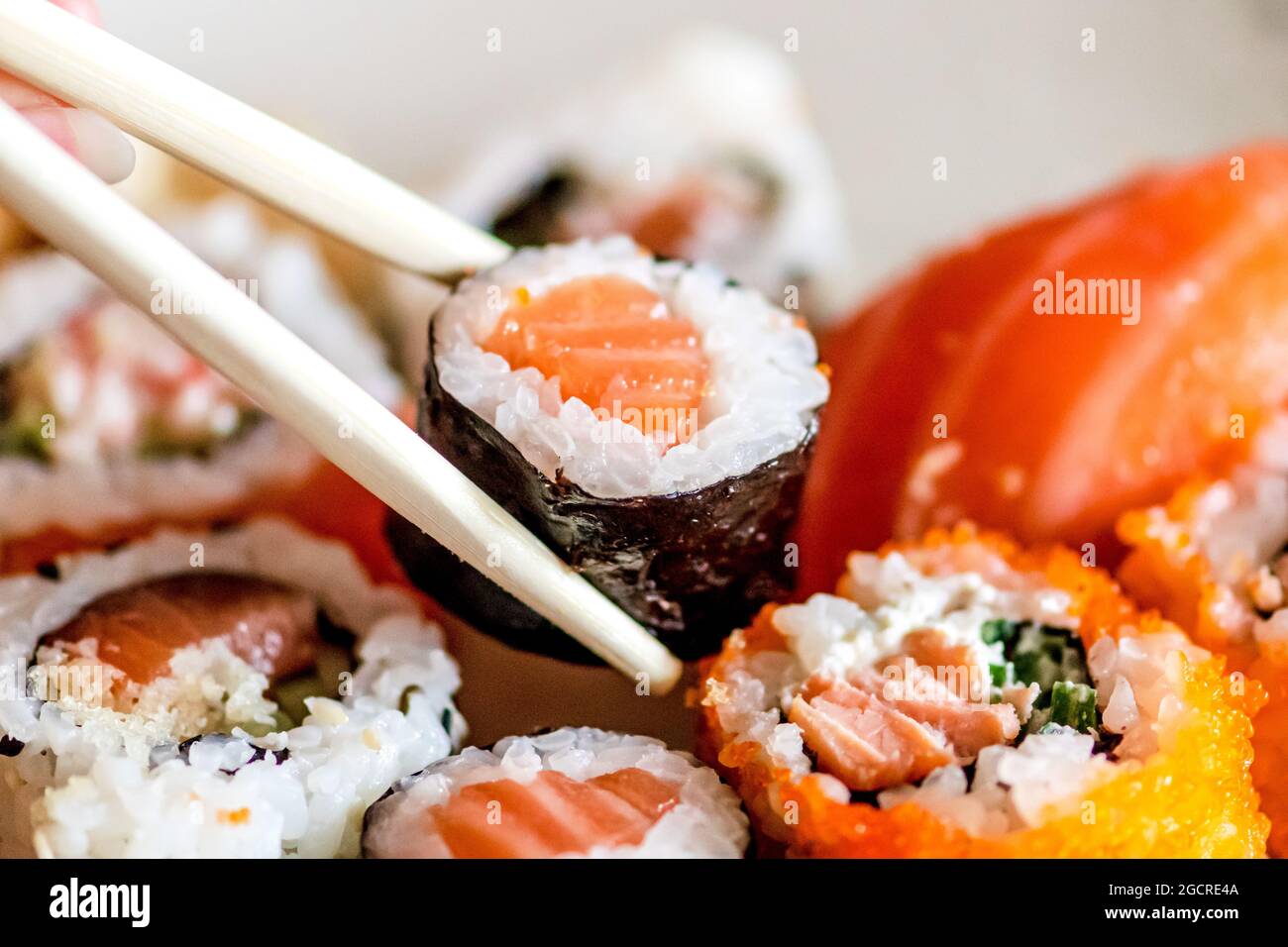 Mangiare vari sushi. Maki, uramaki, hosomaki, sahimi e nigiri in un piatto con bacchette di bambù, primo piano Foto Stock