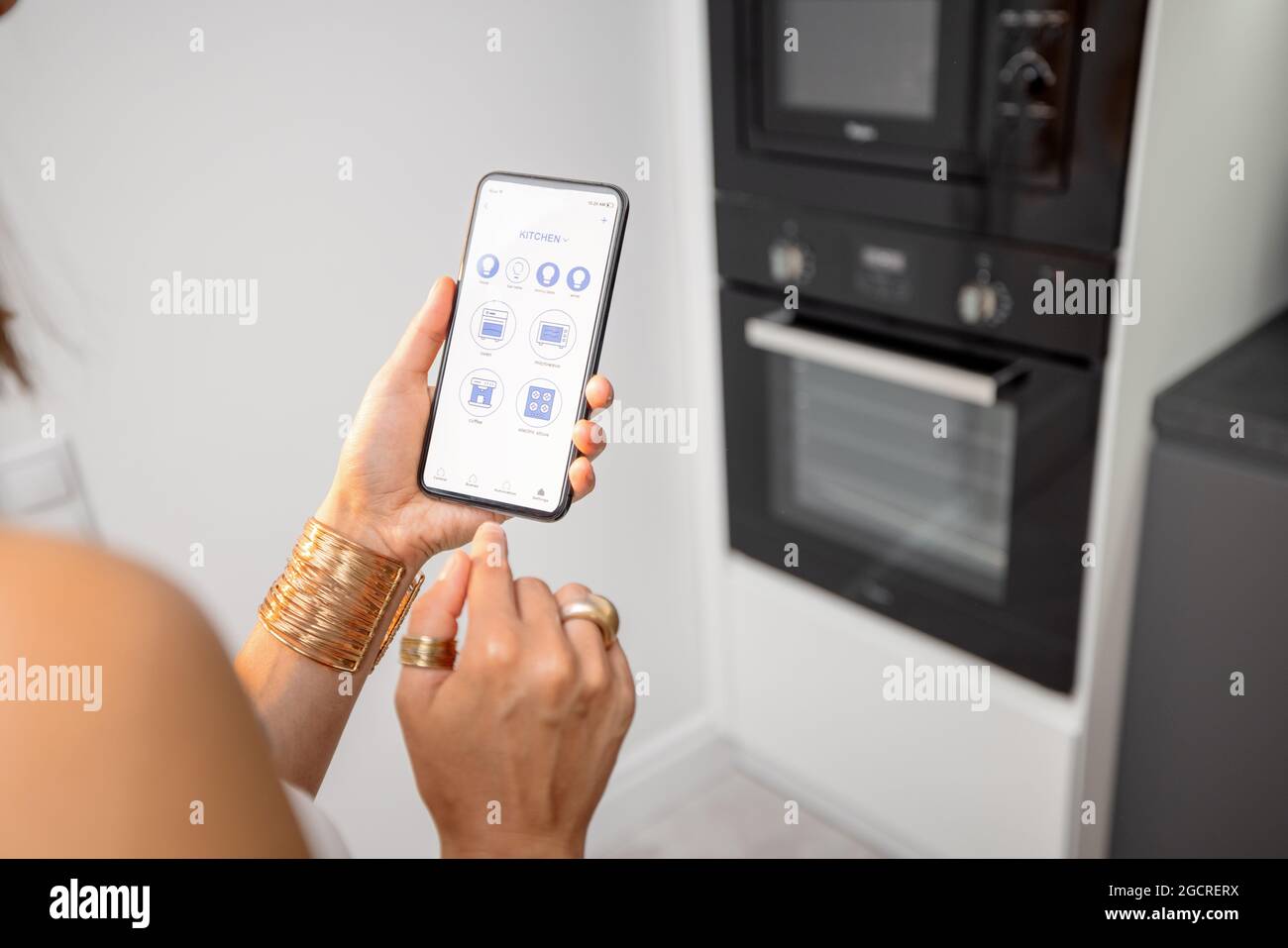 Controllo dei dispositivi intelligenti con il telefono in cucina Foto Stock