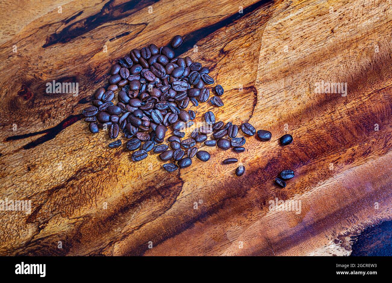Macro fotografia vista dall'alto di un mucchio di chicchi di caffè appena tostati su sfondo di legno. Primo piano dettagliato ad alta risoluzione di chicchi di caffè tostati marroni Foto Stock