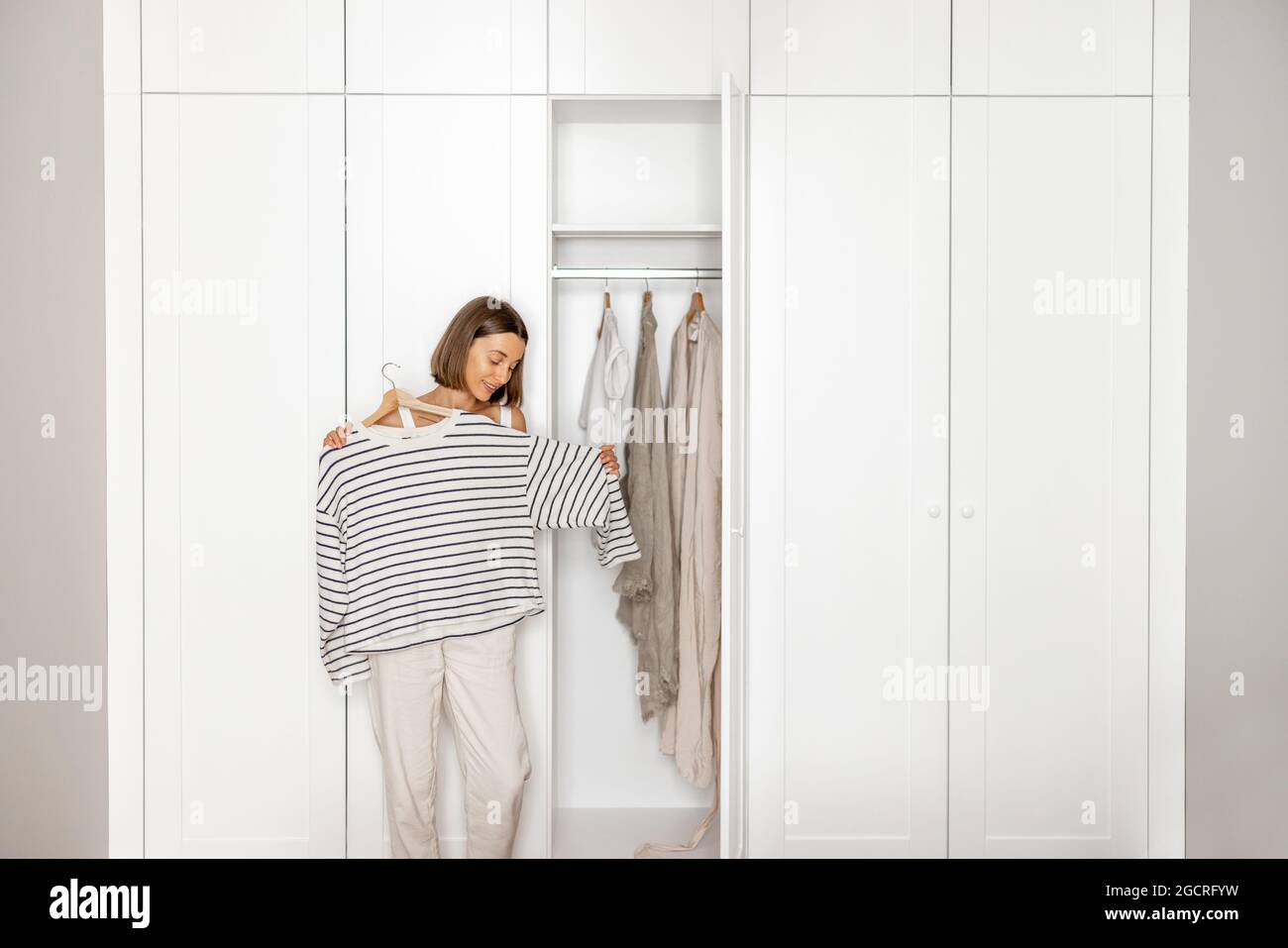 La giovane donna sceglie cosa indossare vicino all'armadio Foto Stock
