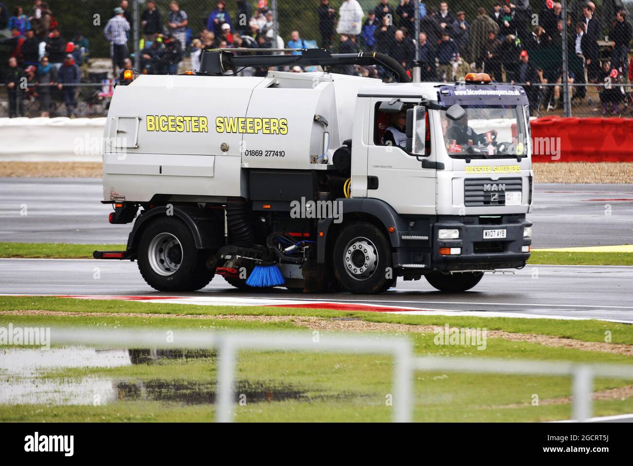 Una spazzatrice viene utilizzata per provare ad asciugare il circuito dopo che la qualifica è ritardata dalla pioggia. Gran Premio di Gran Bretagna, sabato 7 luglio 2012. Silverstone, Inghilterra. Foto Stock