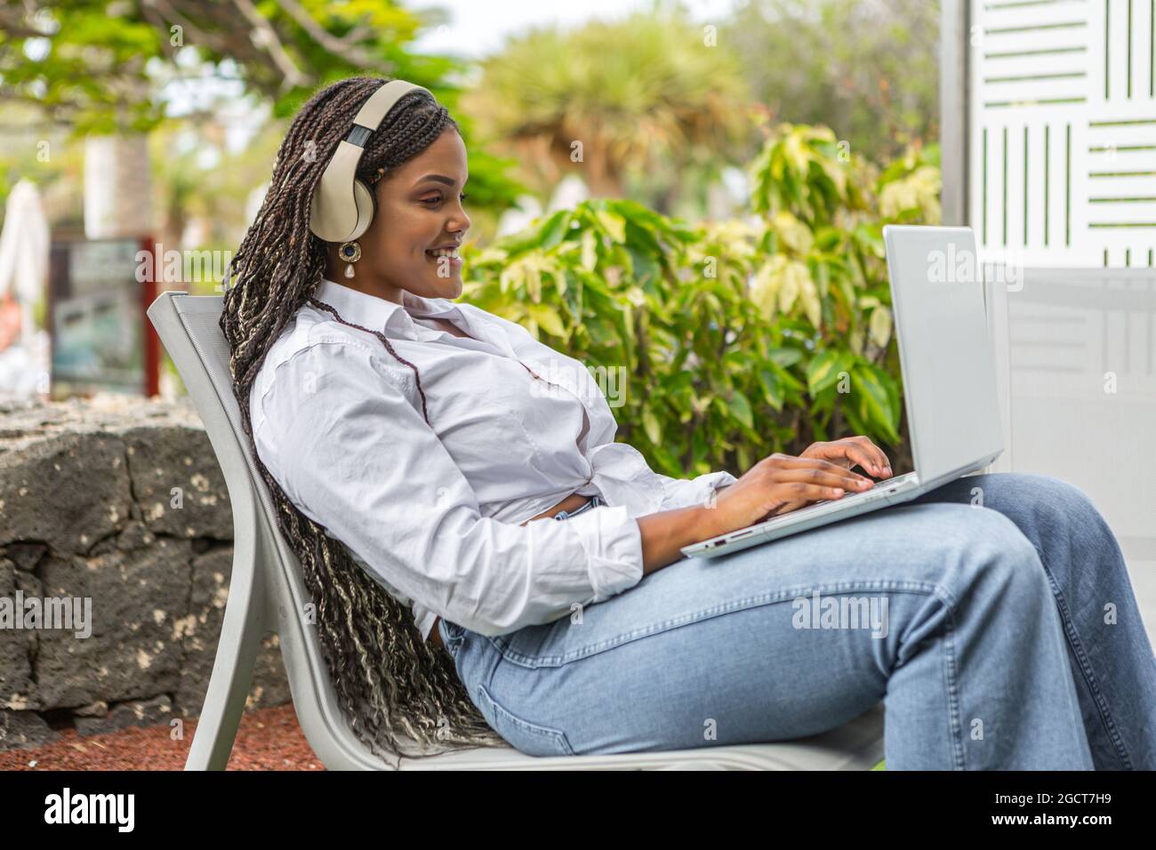 Donna che si rilassa all'aperto con il computer portatile mentre ascolta la musica. Donna afro-americana che si gode la giornata. Foto Stock