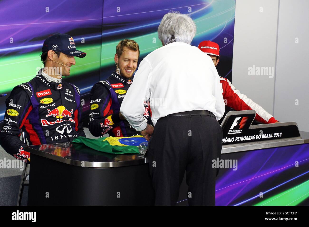 Bernie Ecclestone (GBR) il CEO di Formula One Group (FOM) presenta una bandiera brasiliana, firmata da sé e da tutti i piloti, per Sebastian Vettel (GER) Red Bull Racing a firmare, da presentare a Mark Webber (AUS) Red Bull Racing. Gran Premio del Brasile, domenica 24 novembre 2013. San Paolo, Brasile. Foto Stock
